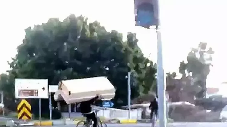 Muğla'da bir kişi, bisiklet sürerken omzunda kanepe taşıdı