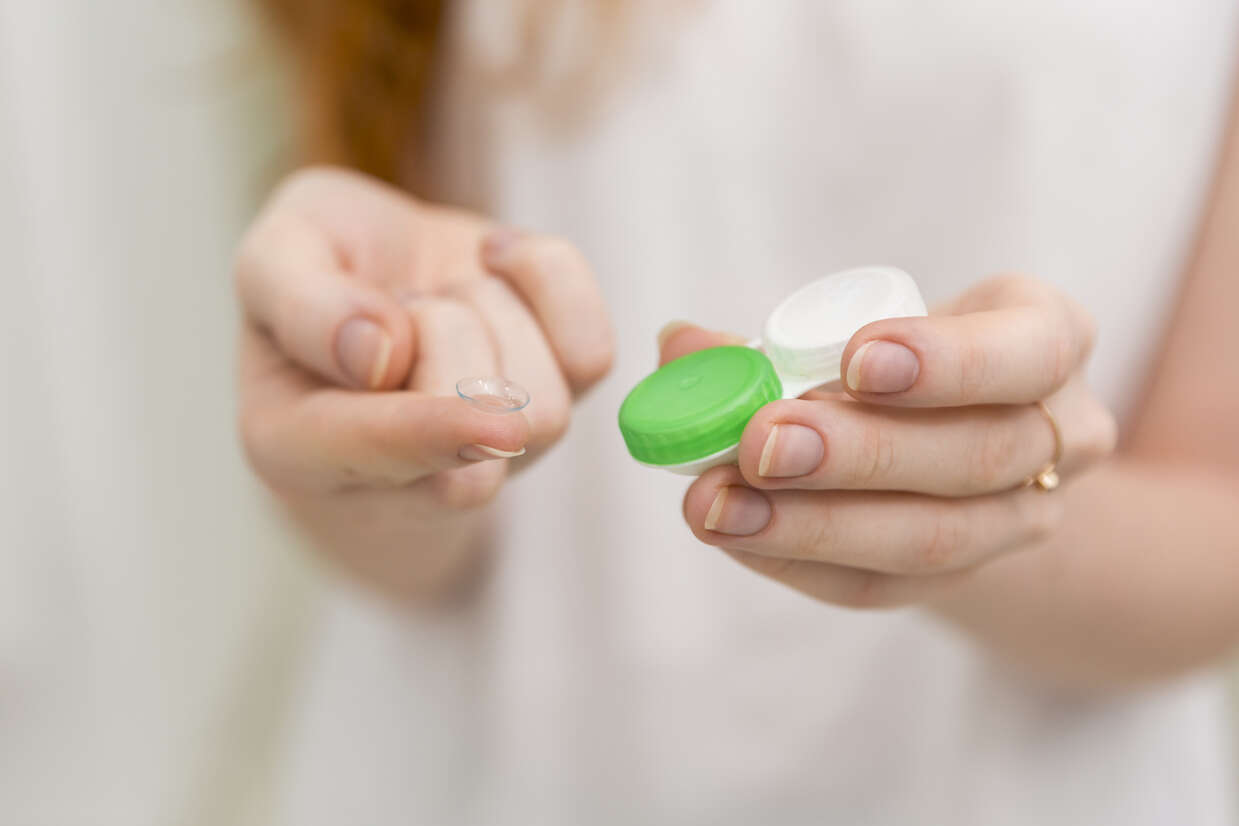 1781866032-close-up-woman-hand-holding-contact-lens-it-s-container