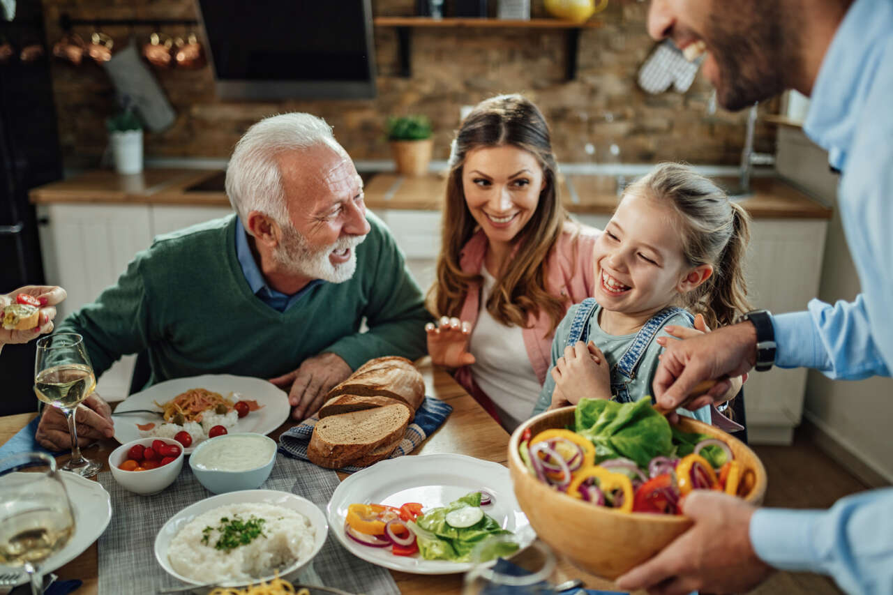 1783496095-happy-extended-family-having-fun-while-talking-lunch-dining-room-focus-is-little-girl