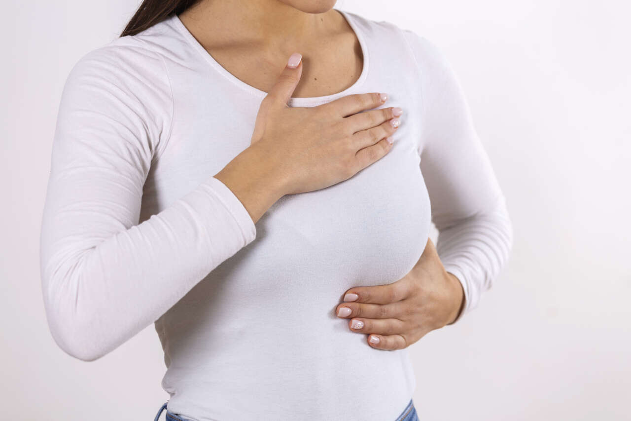 1784615659-woman-hand-checking-lumps-her-breast-signs-breast-cancer-gray-background-healthcare-concept-closeup-woman-s-hand-breast-showing-cancer-symptom
